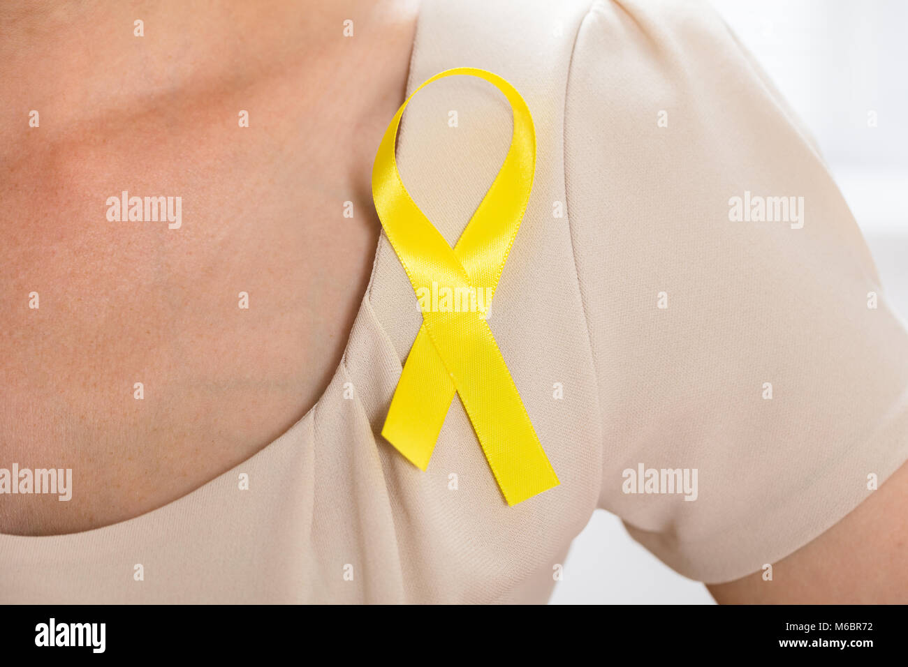 Close-up Of A Woman With Gold Ribbon To Support Childhood And Bladder Cancer Stock Photo