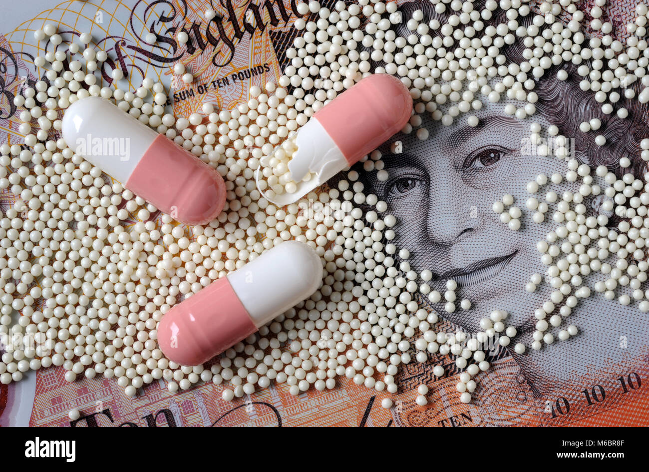 DRUG CAPSULES WITH CONTENTS WITH NEW BRITISH £10 NOTE RE HEALTH COSTS PHARMACEUTICAL COSTS NHS HEALTH TESTING ETC UK Stock Photo