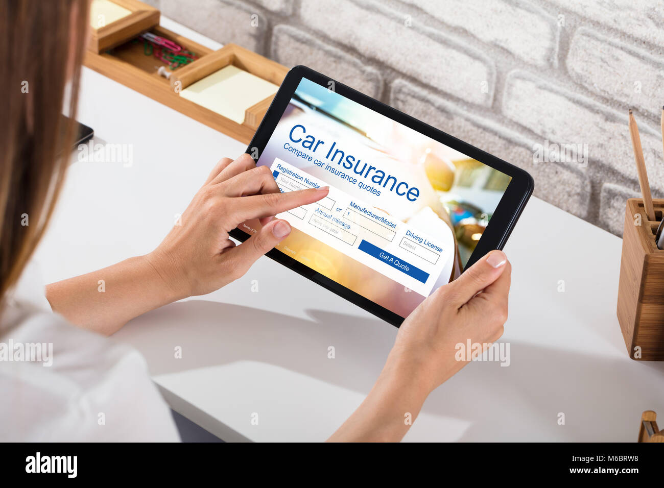 Close-up Of A Businesswoman Filling The Car Insurance Form On Digital Tablet Over Desk Stock Photo