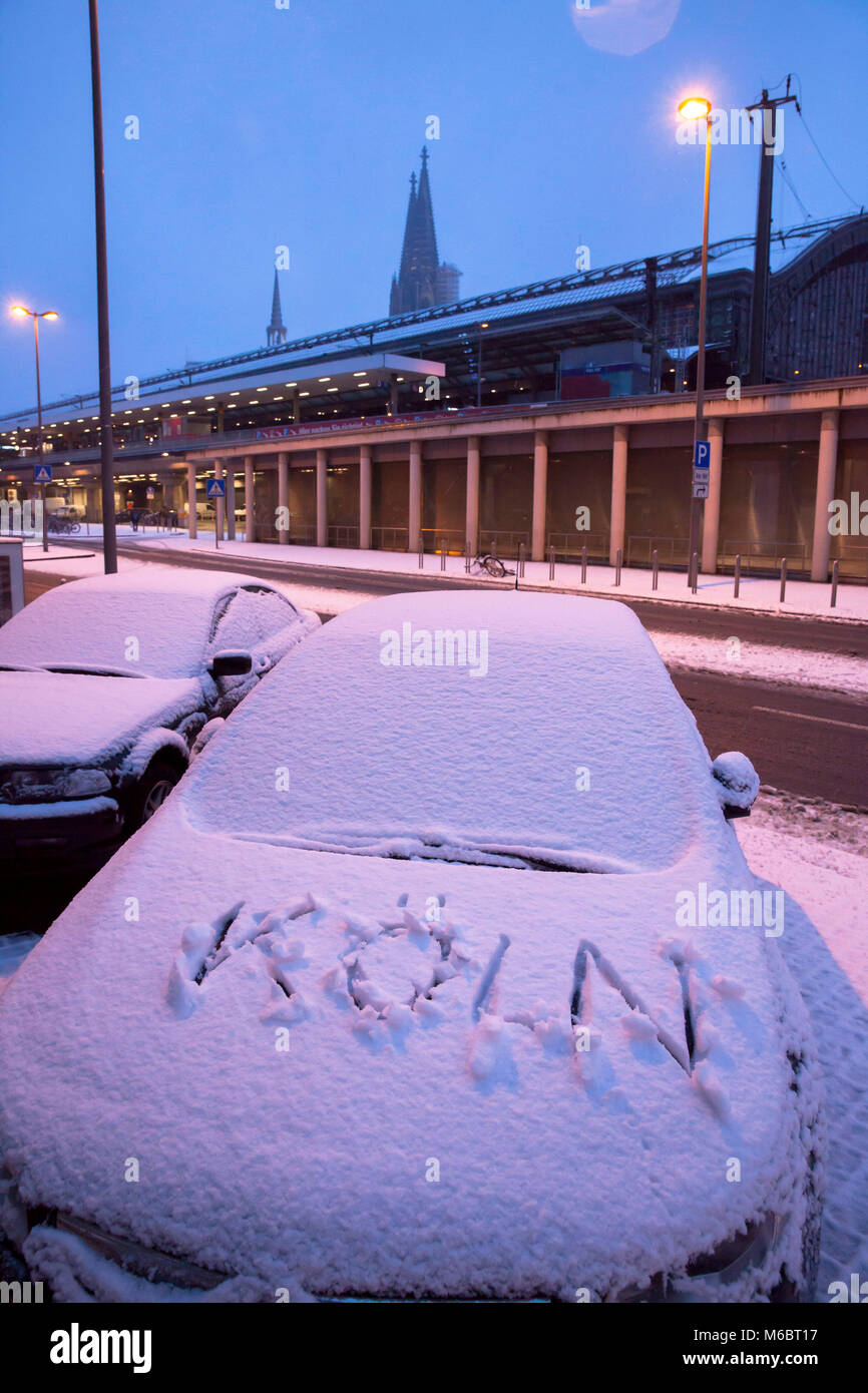 Germany, Cologne, snow-covered car with Koeln (Cologne) writing on the hood near the main station, in the background the cathedral.  Deutschland, Koel Stock Photo