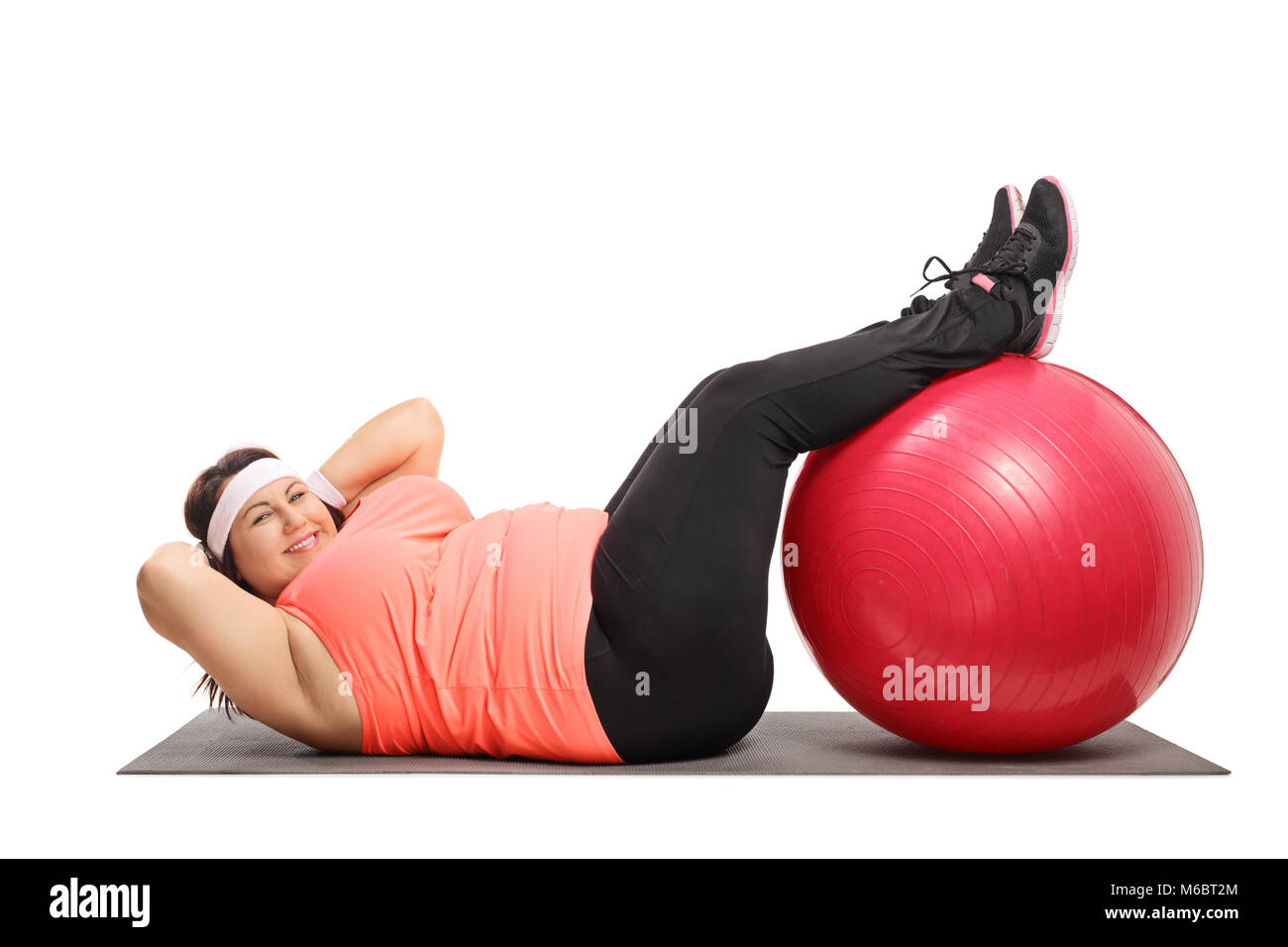 Overweight woman doing crunches on an exercise mat isolated on white background Stock Photo