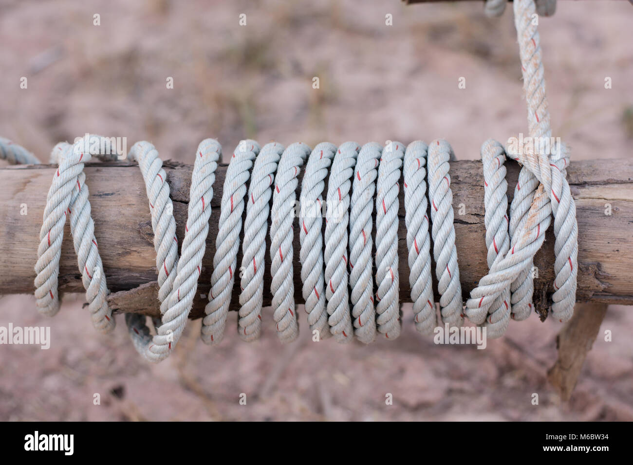 A rope is tied in a knot around a fence post , rope tied knot wood pole