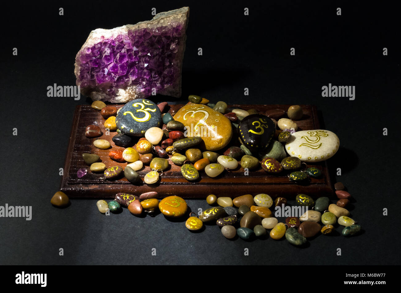 Amethyst crystal and colorful stones painted with Om symbol Stock Photo