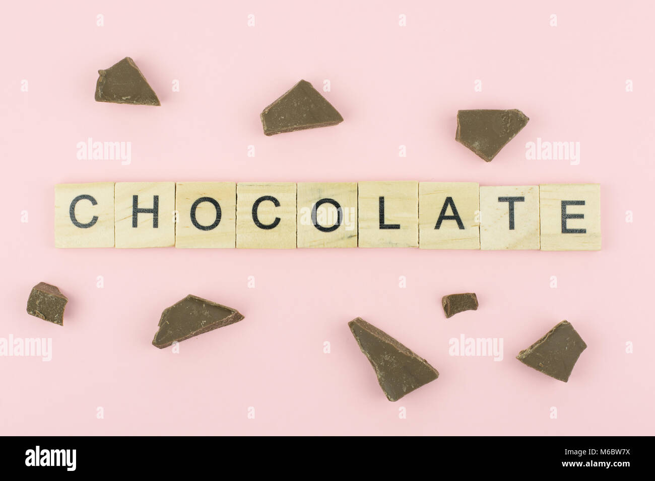 Text wooden blocks spelling the word chocolate on pink background Stock