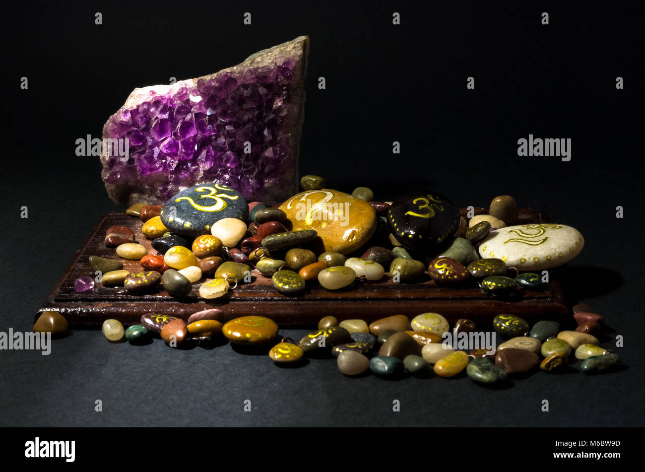 Amethyst crystal and colorful stones over a wooden board Stock Photo