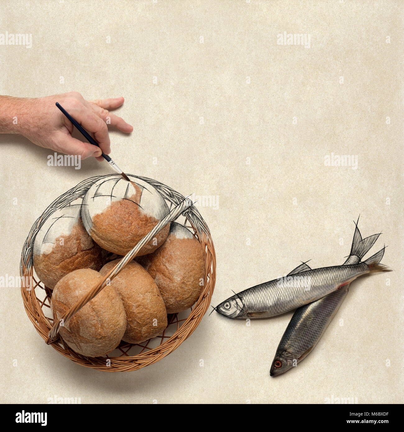 Hand painting over a drawing of five loaves of bread and two fish. Christian concept about preparing a bible study or a message on this. Stock Photo