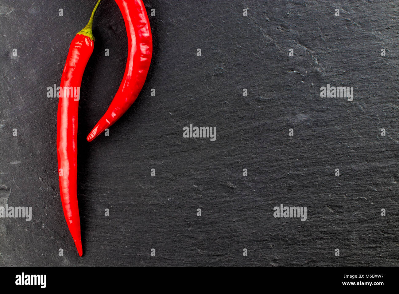 Red hot chili peppers and peppercorns on black background, top view with copy space Stock Photo