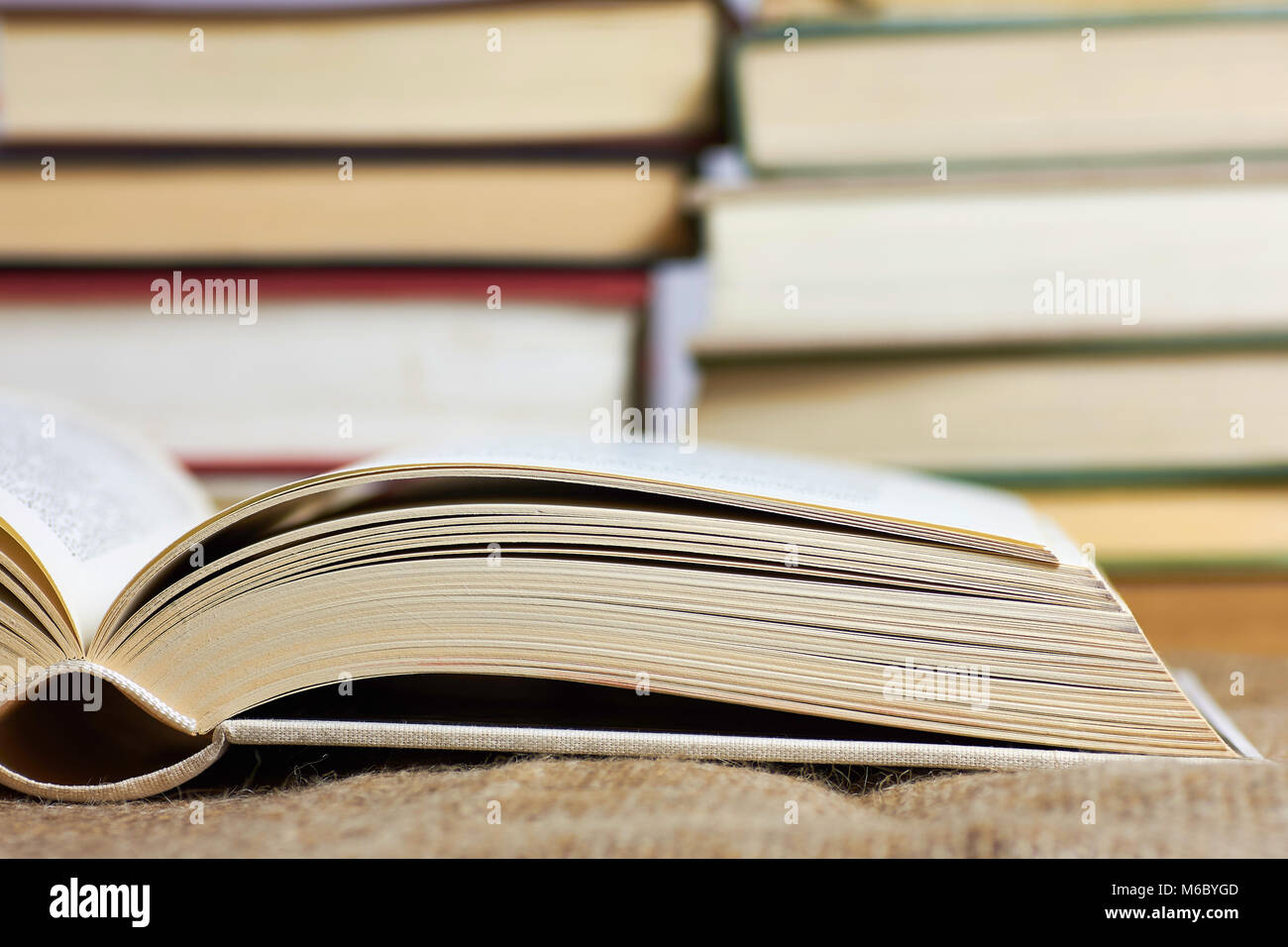 An open book in a hard cover with blurred books in the background Stock Photo