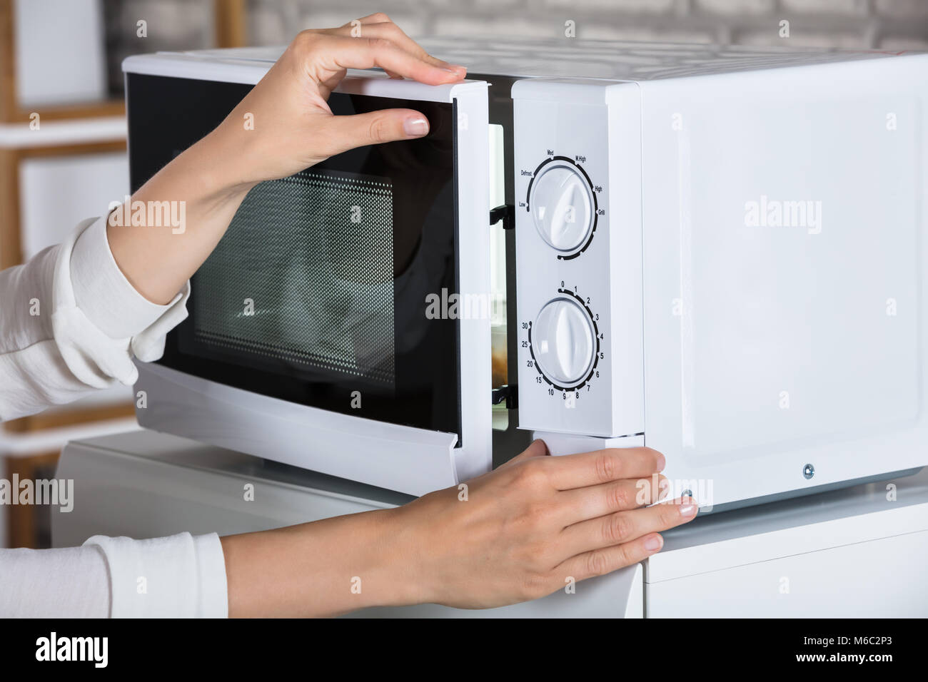 Woman's Hands Closing Microwave Oven Door And Preparing Food At Home Stock Photo