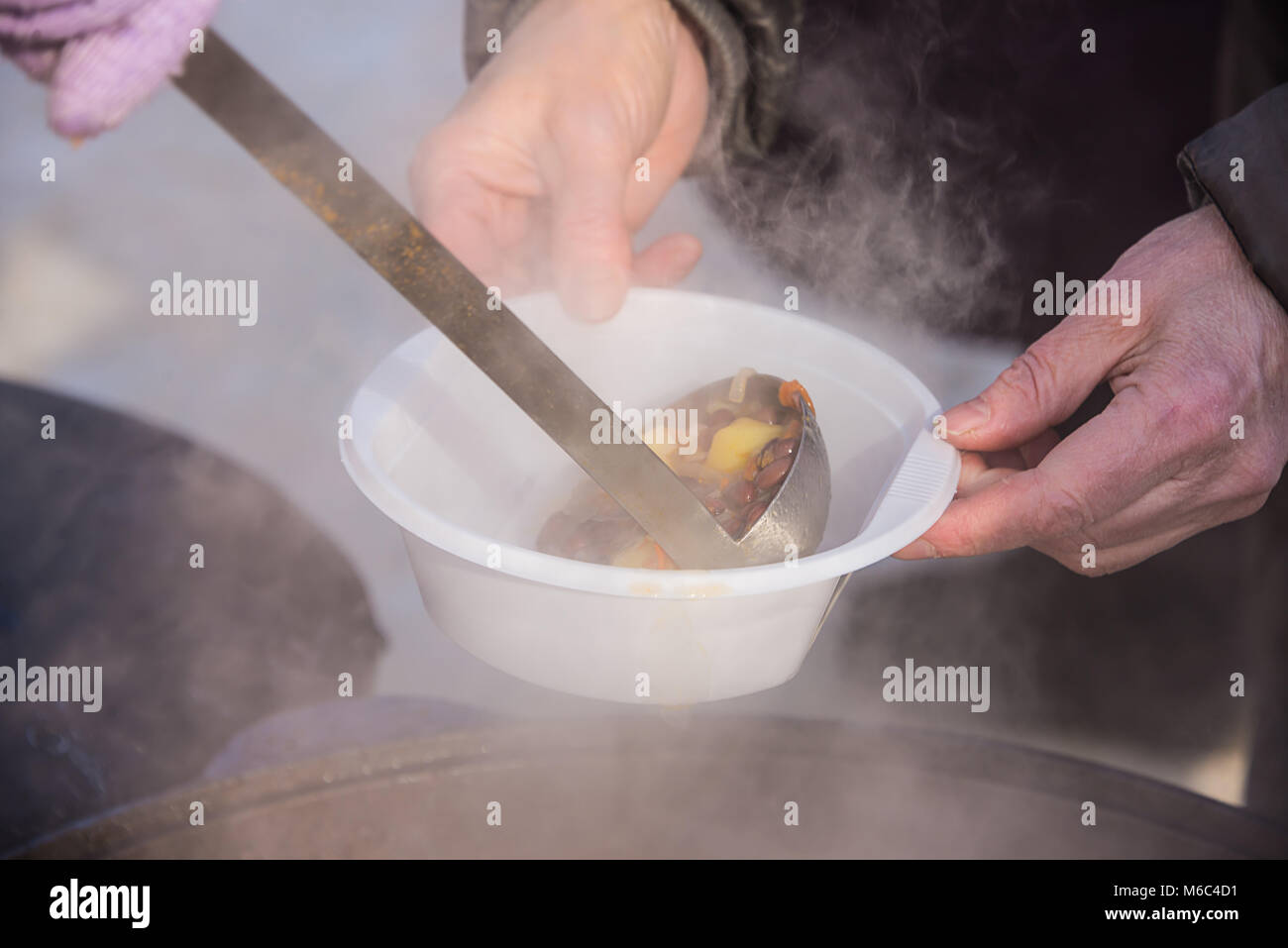 feeding homeless people on the street, social problems, hungry people eat Stock Photo