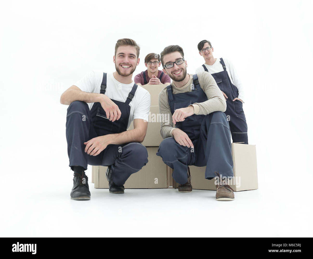 Smiling young delivery men holding stack of boxes. Isolated on w Stock Photo
