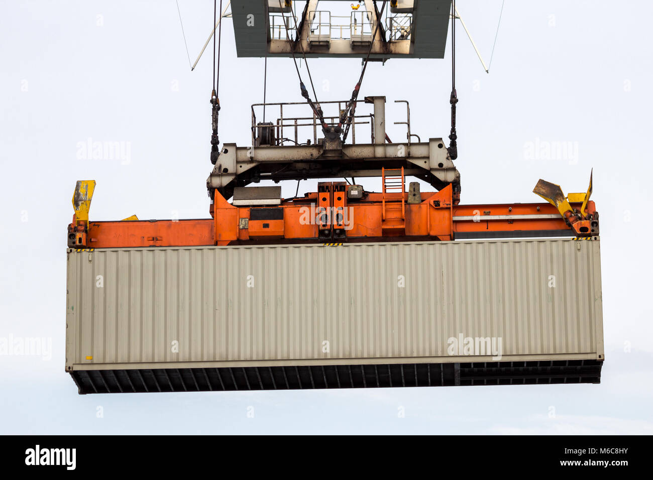 Cargo container lifted by a gantry crane in a industrial shipping terminal in a port. Stock Photo