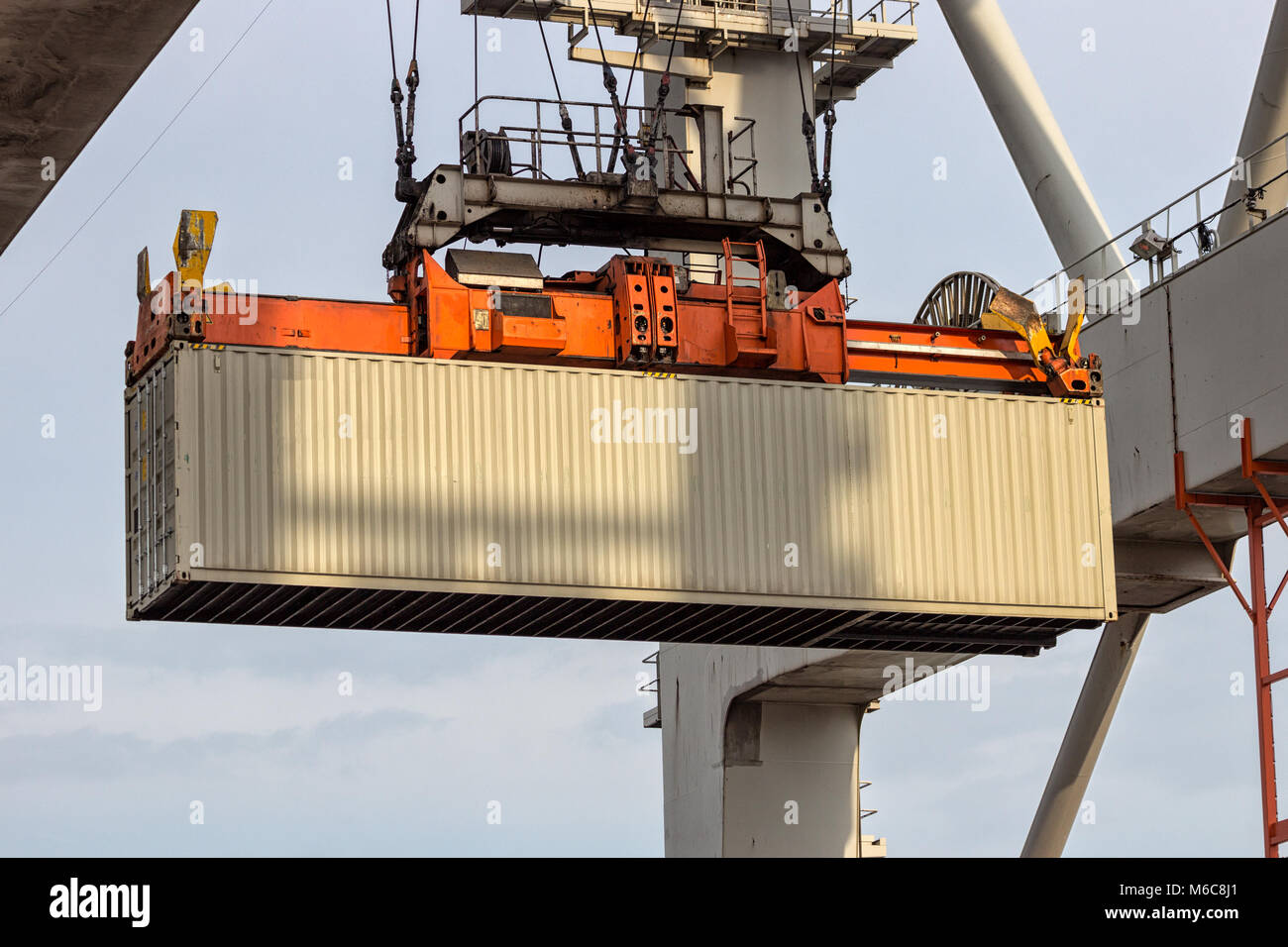 Cargo container lifted by a gantry crane in a industrial shipping terminal in a port. Stock Photo