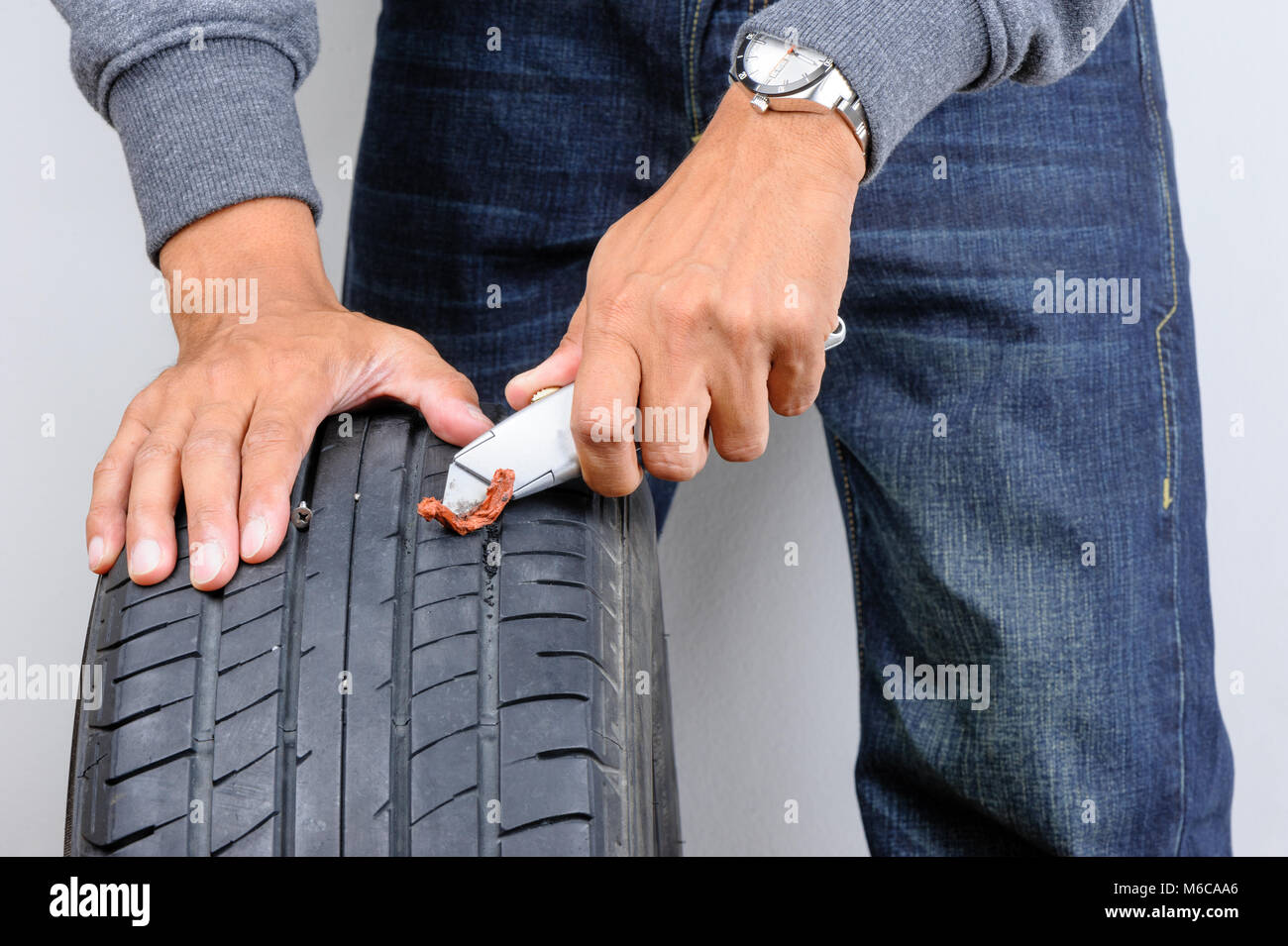 The man repairing flat car tire with repair kit, Tire plug repair kit