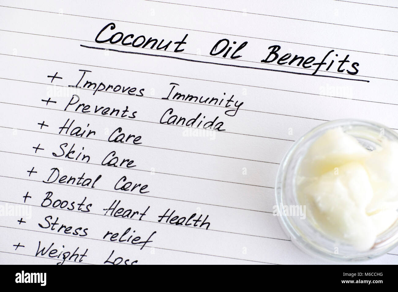 List of Coconut Oil Benefits and jar with coconut oil. Close-up. Stock Photo