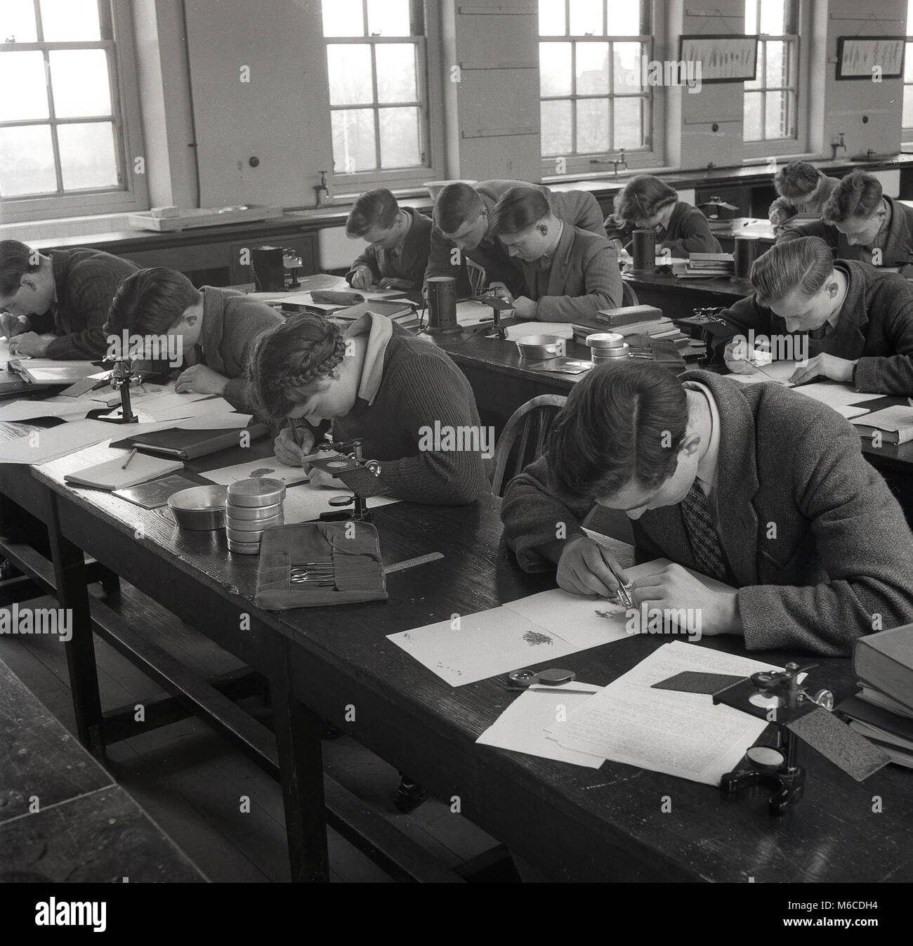 1950s, historical picture, a group of young adult students doing a geometry class at a technical college, England, UK. The male teacher is seen here helping one of the students with his work. Stock Photo