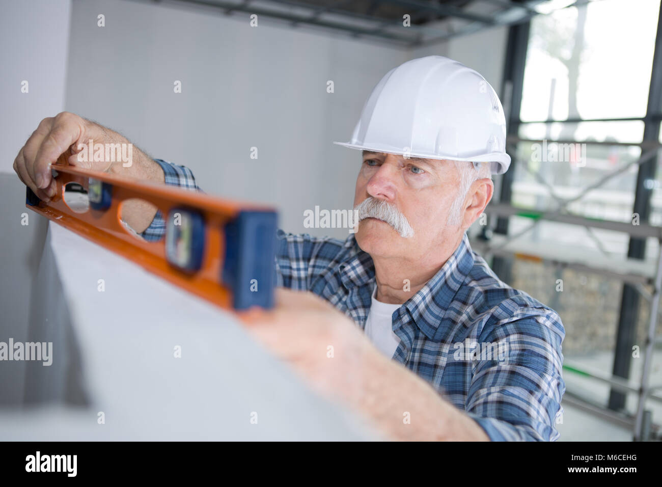 builder putting spirit level on the wall division Stock Photo - Alamy
