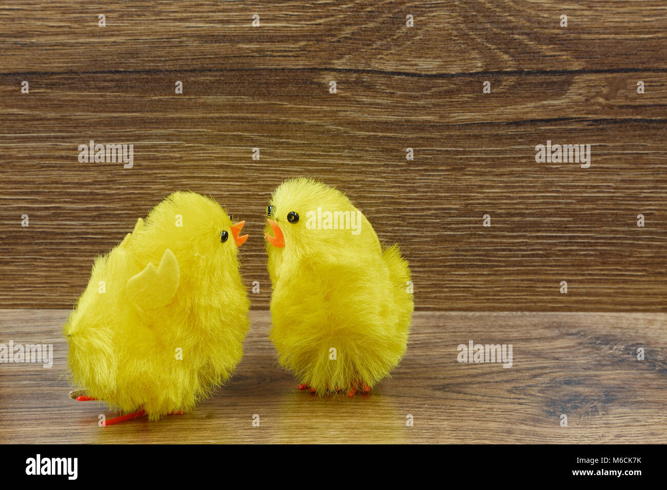 Two yellow chickens on a wooden background as interesting Easter decoration.Horizontal view. Stock Photo