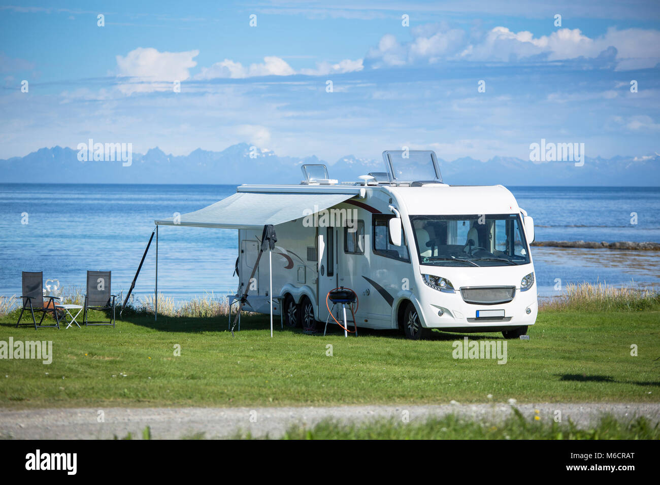Motorhome parking nearby the water at Engeloya, Norway. The wall of Lofoten Oslands is rising in the horizon. Stock Photo