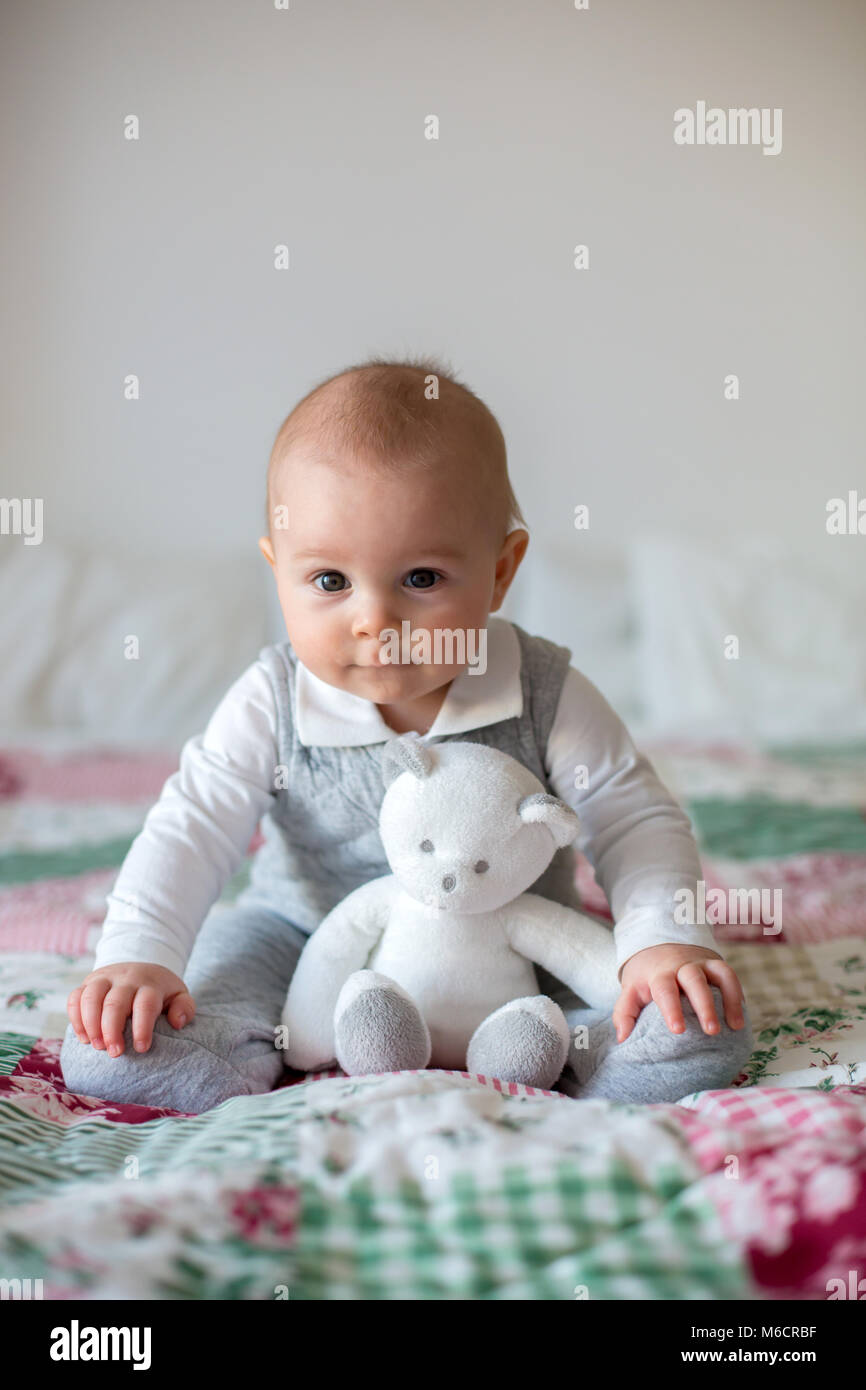 Portrait of a cute smiling infant baby boy playing with teddy bear toy ...