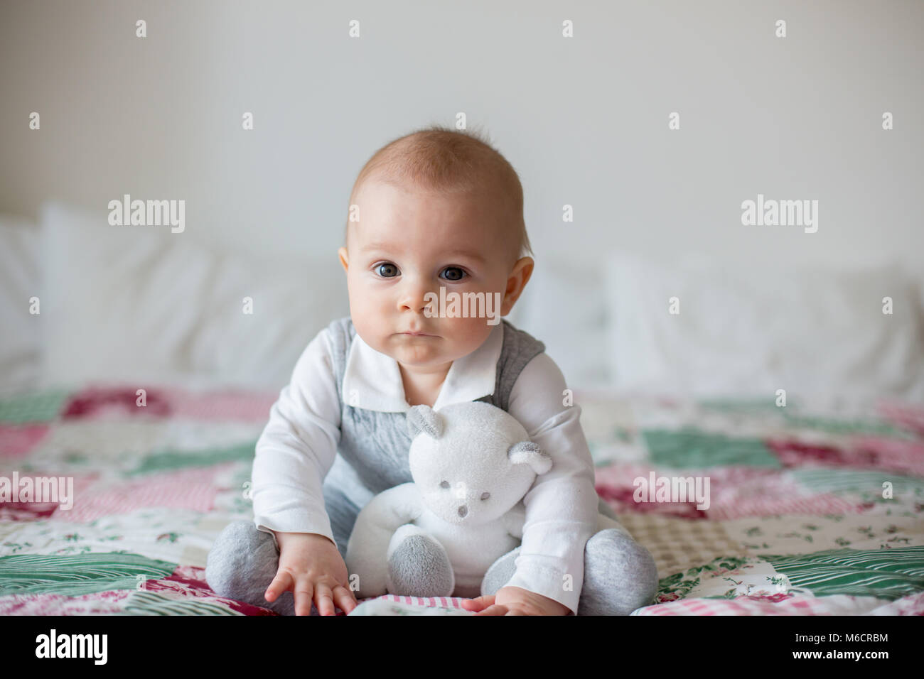 Portrait of a cute smiling infant baby boy playing with teddy bear toy ...