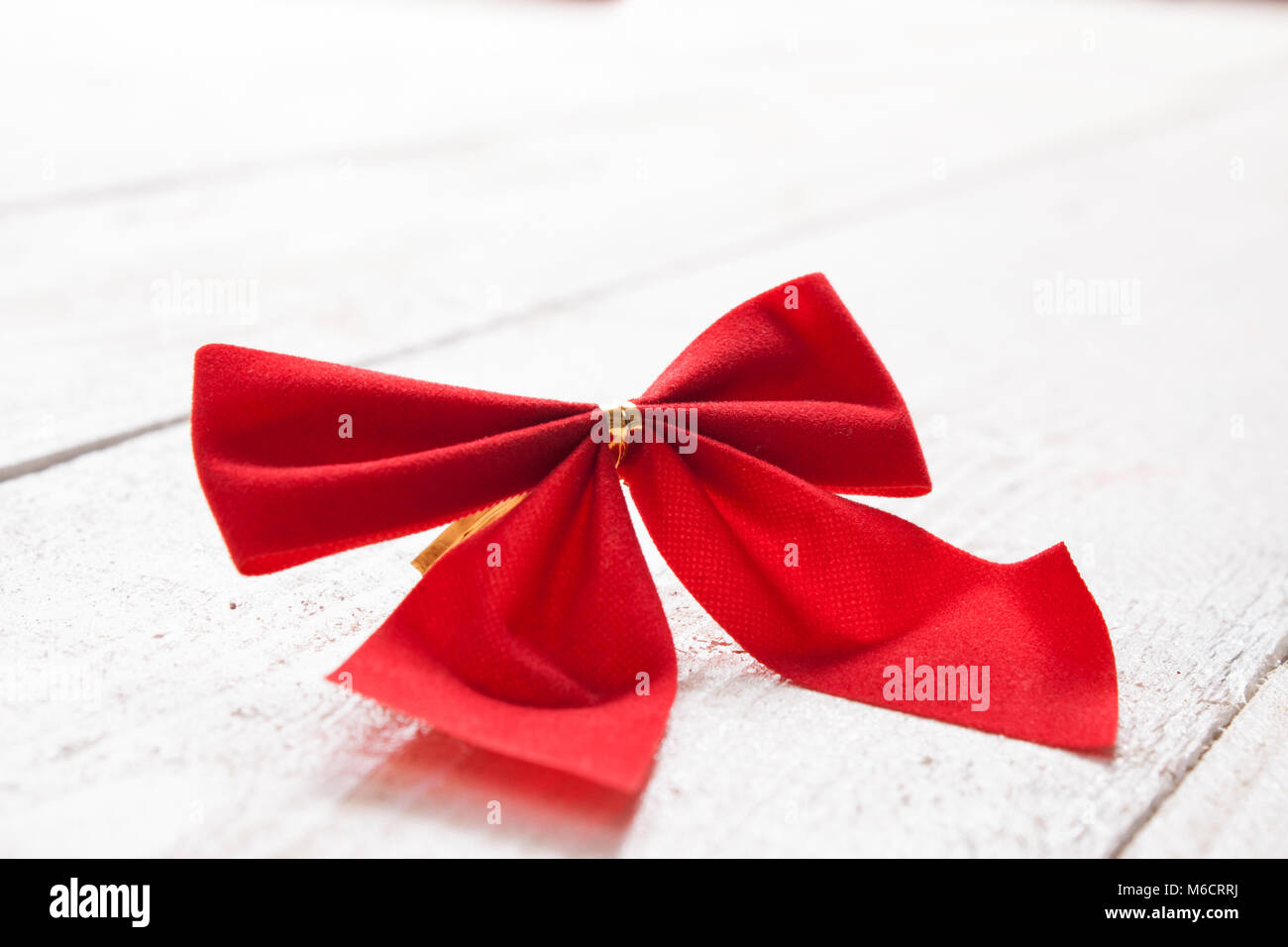 Decorative red ribbon and bow on a background of white painted rustic ...