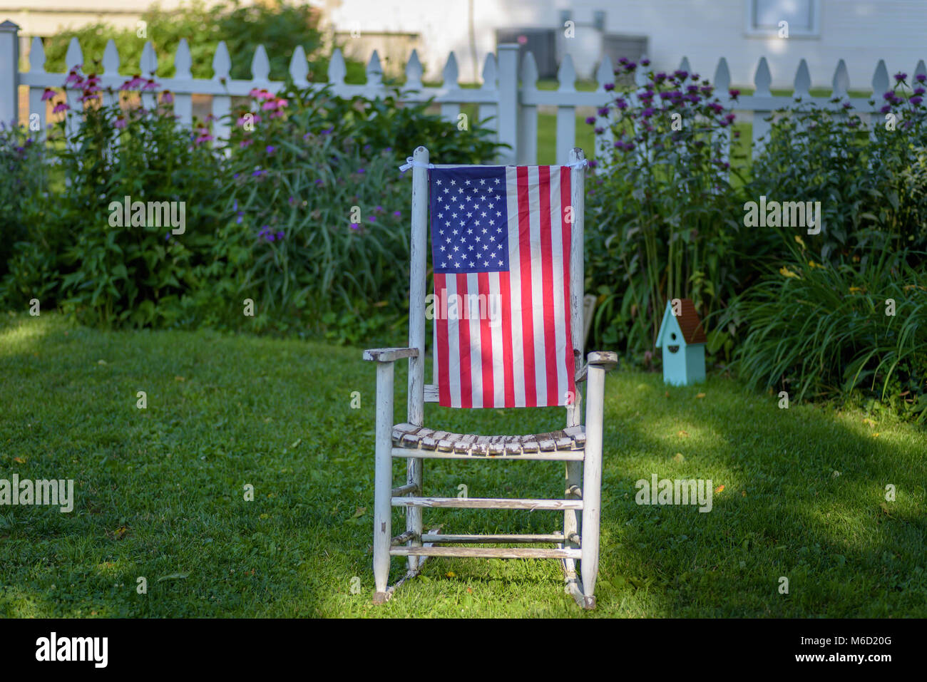 closeup of a empty rustic old rocking chair with American flag hanging ...