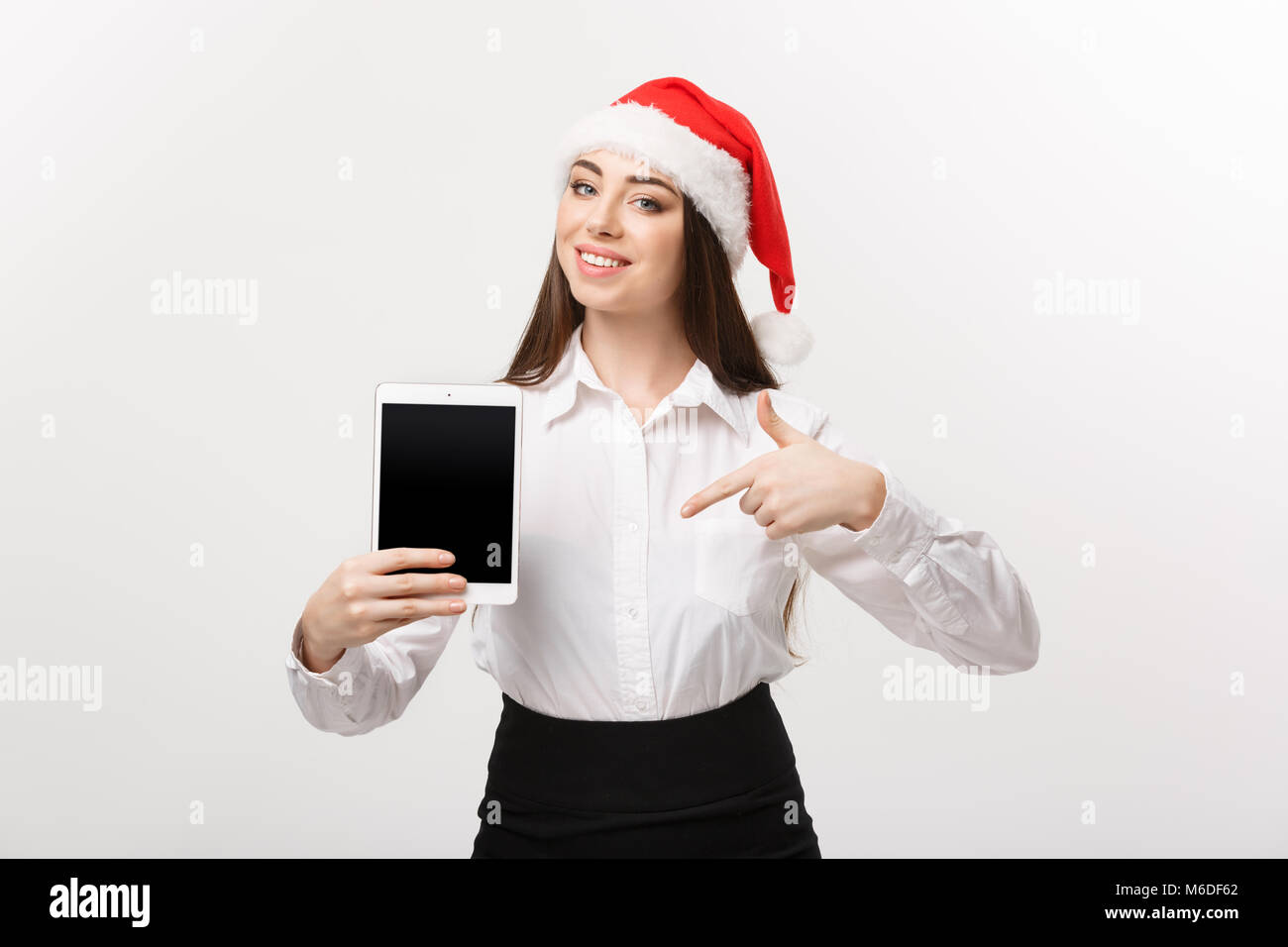 Business Concept - young caucasian business woman in Christmas theme showing and pointing to digital tablet. Stock Photo