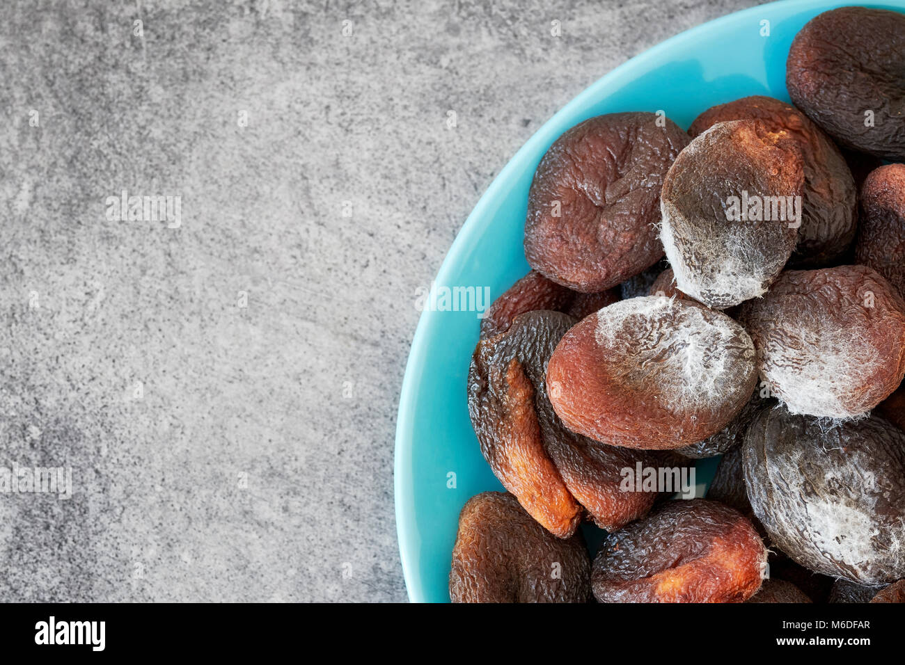 Moldy dried apricots on a plate, space for text. Stock Photo