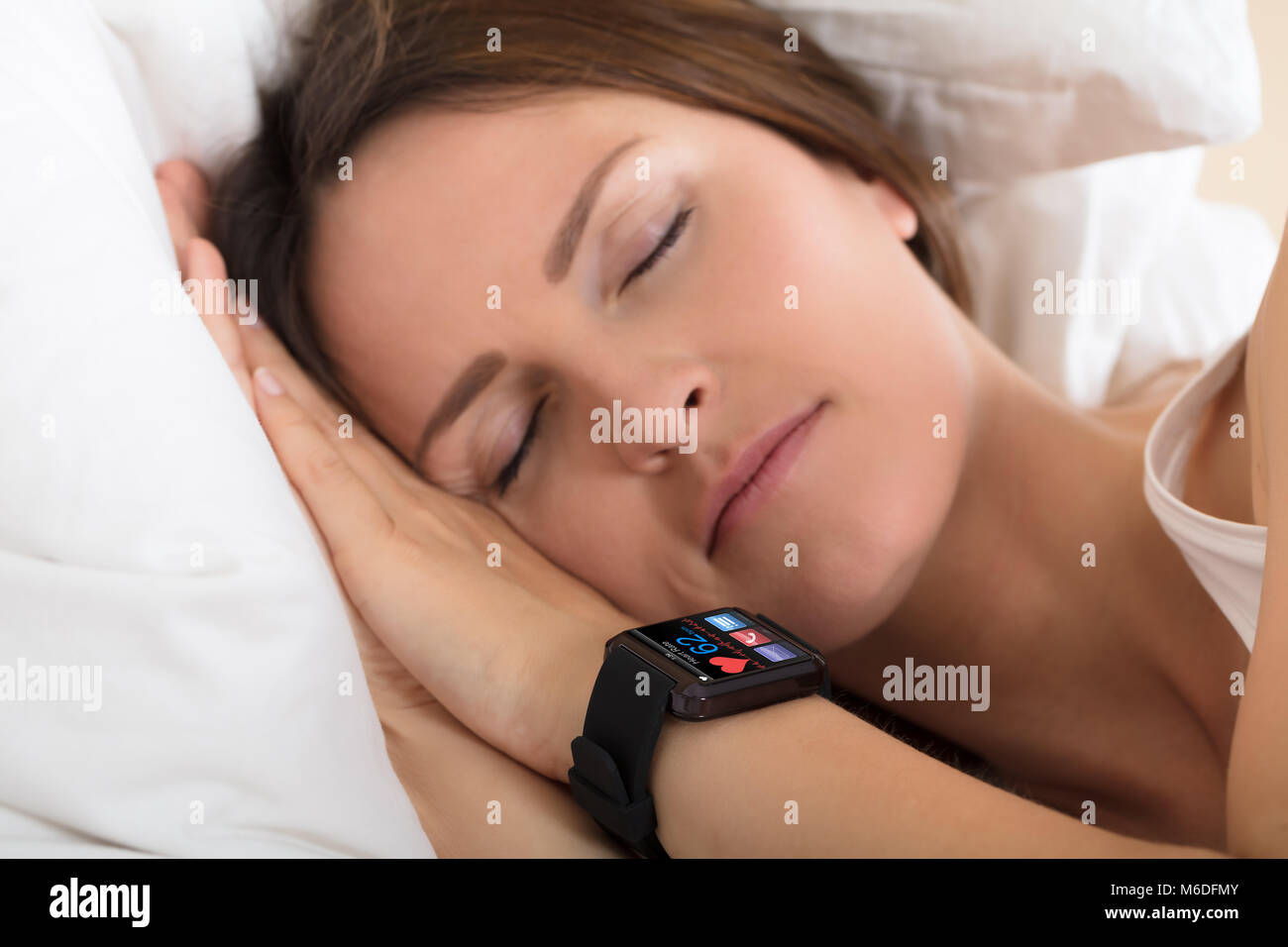 Close-up Of A Woman Sleeping With Smart Watch Showing Heartbeat Rate On Bed Stock Photo