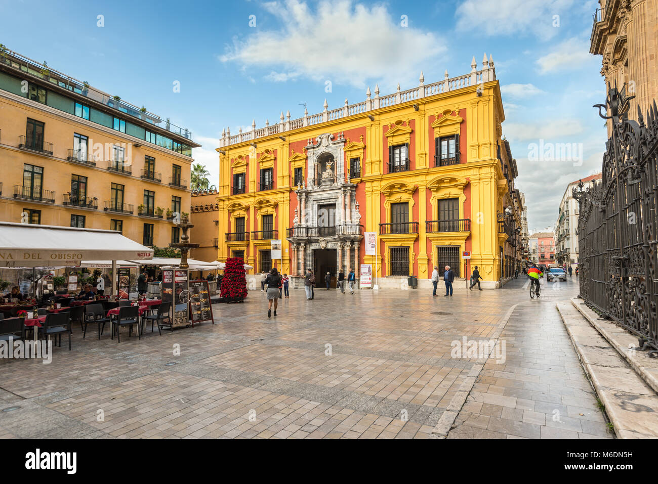 Malaga, Spain - December 7, 2016: Episcopal palace facade and tourist sitting on the restaurants terraces and walking around Bishop Square in Malaga c Stock Photo