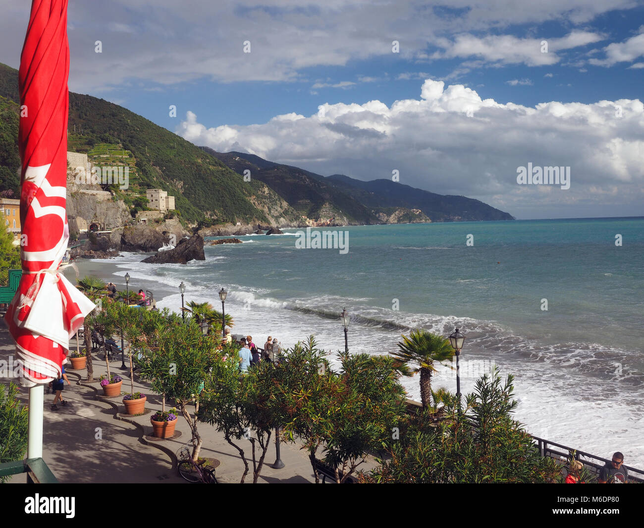 MONTEROSSO, ITALY-SEPT. 22: Tourists walk the tree lined promenade over the  Mediterranean Sea in Monterosso in Cinque Terre, Italy with old town in t Stock Photo
