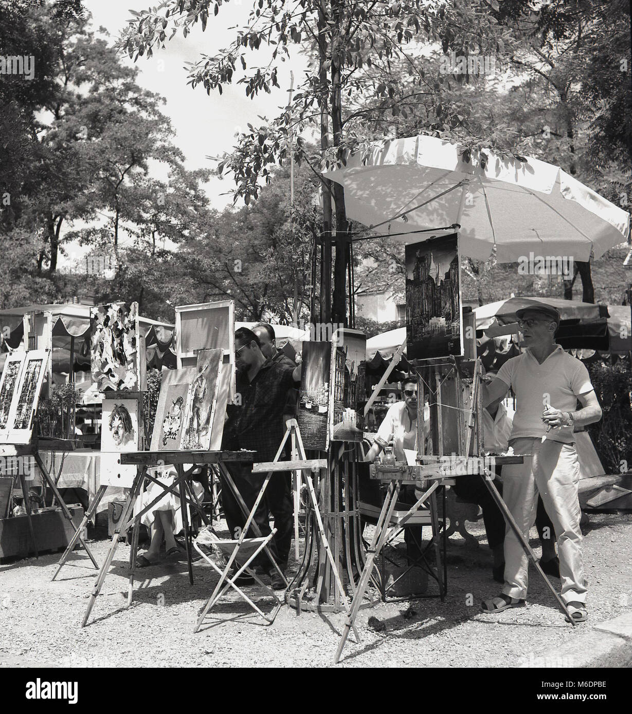 1950s, Paris, France, summertime and parisian street artists working on their paintings under shade in the square at Montmartre. Stock Photo