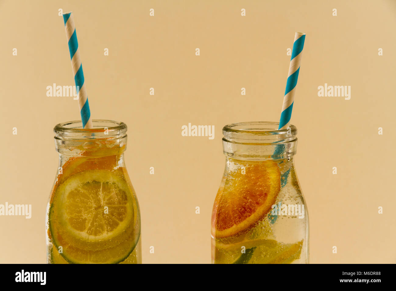 Children’s sparkling water drinks in bottles with straw. Slices of orange, lemon and lime. Stock Photo