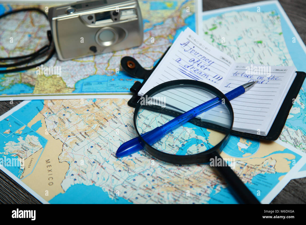 On the table is an Atlas of the United States. Nearby are magnifier, notebook, pen and camera. Travel preparation. Stock Photo