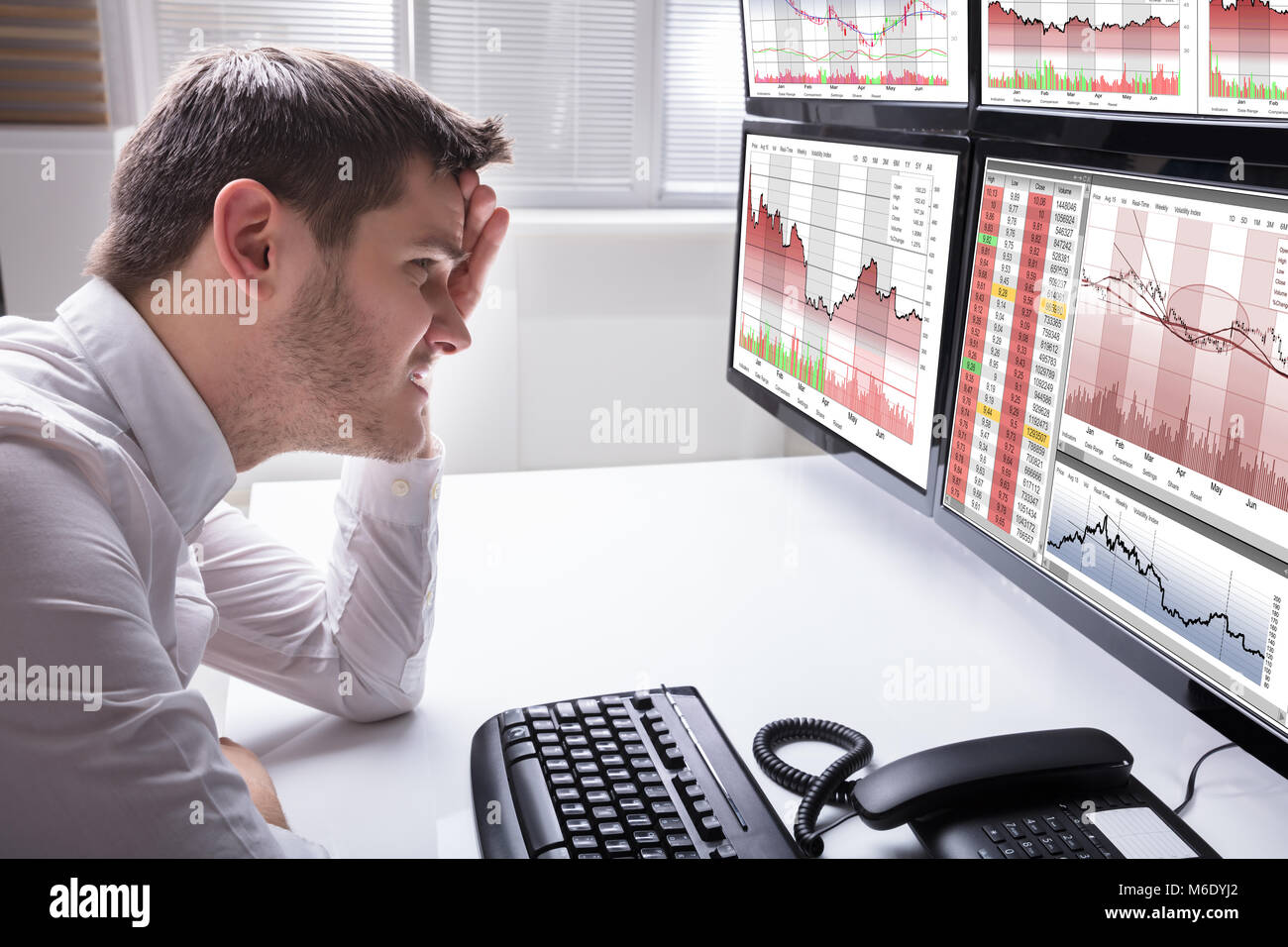 Side View Of A Sad Young Male Operator Looking At Graphs On Multiple ...
