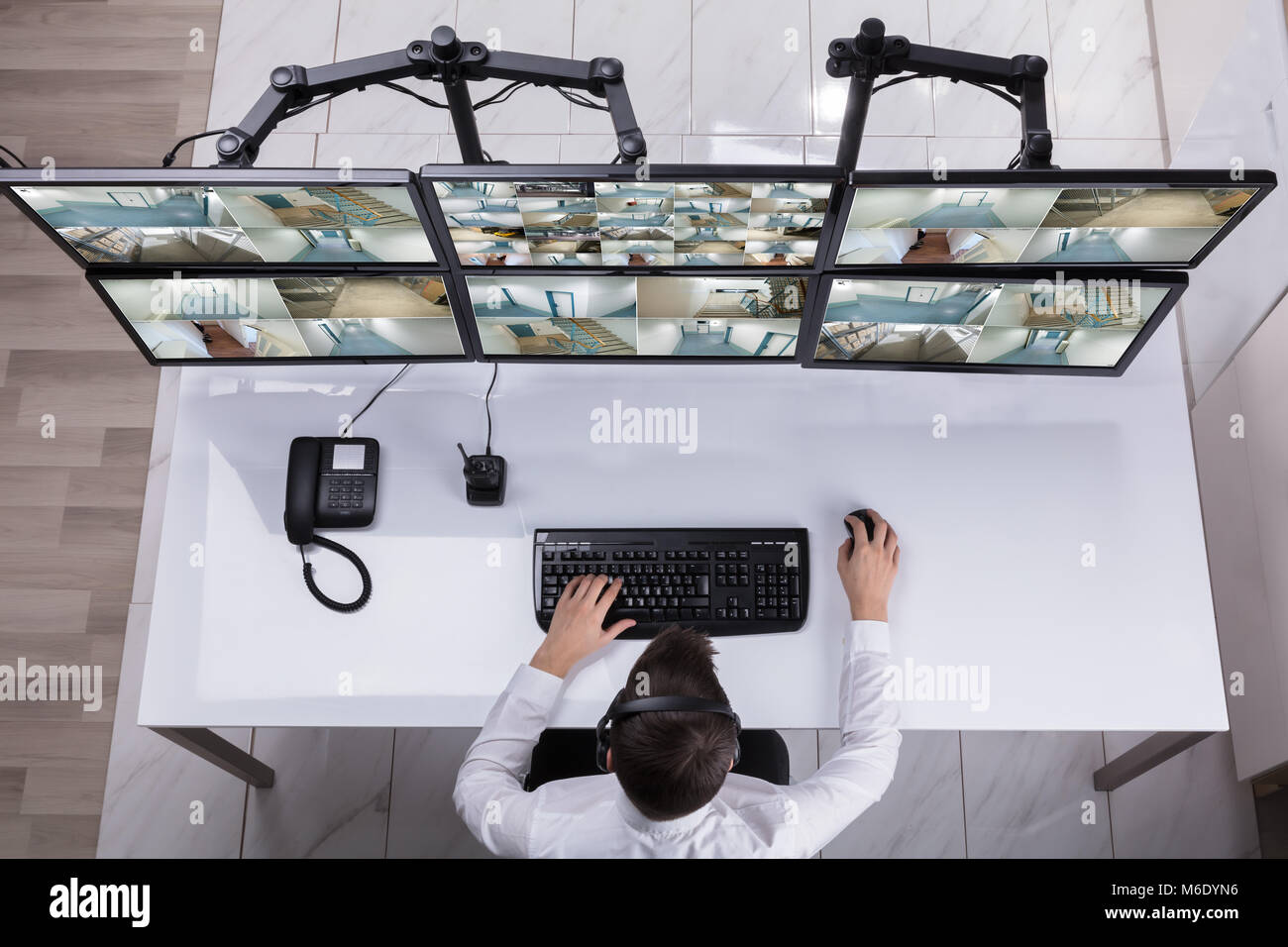 Elevated View Of Male Security Guard Monitoring Multiple Camera Footage ...