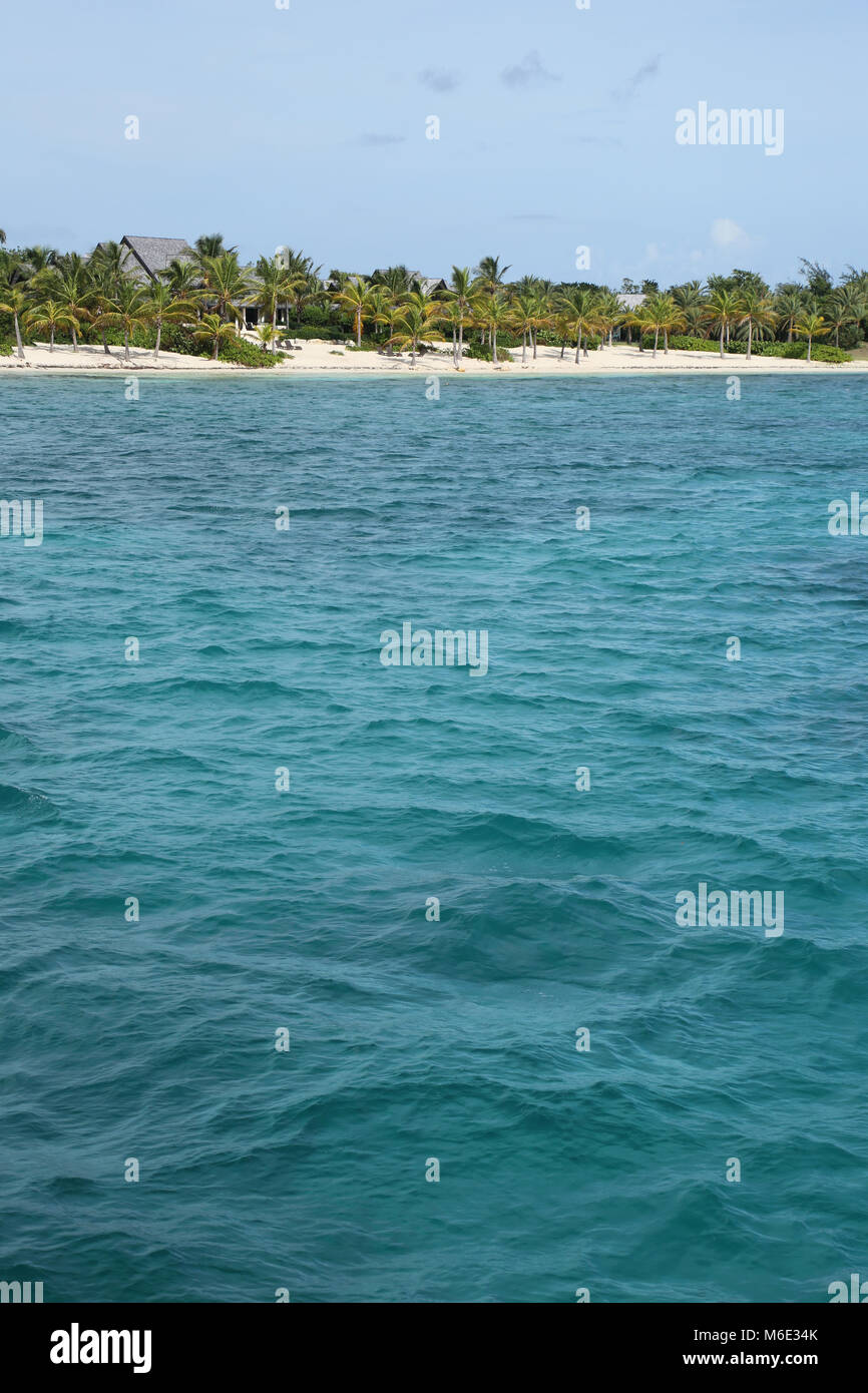 Beautiful tropical beach with turquiose sea & white sand on Green Island, Antigua, Caribbean. Vertical with copy space. Stock Photo