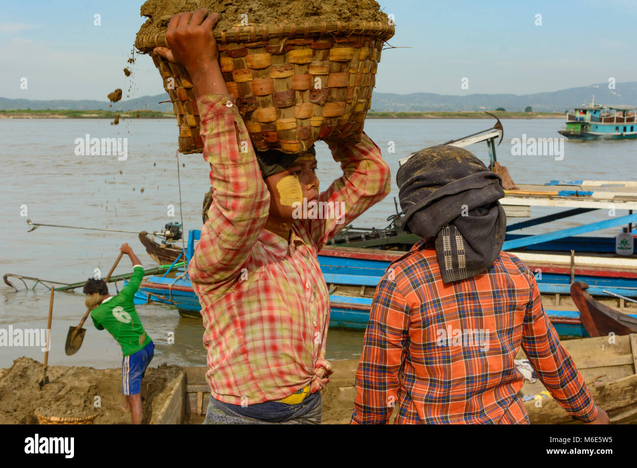 Mandalay: woman man unloading sand with basket from cargo ship at Irrawaddy (Ayeyarwady) River, heavy work, , Mandalay Region, Myanmar (Burma) Stock Photo
