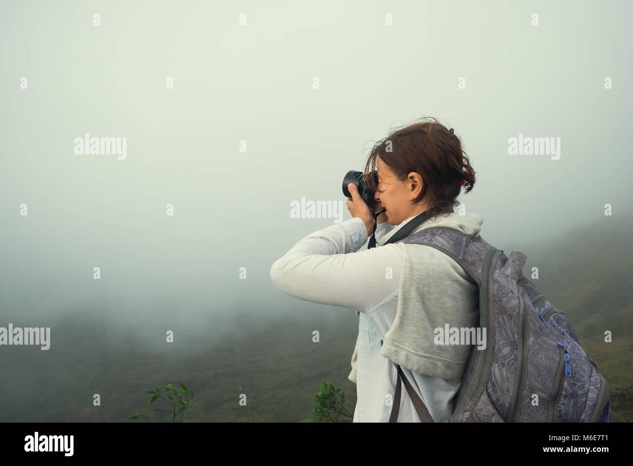 Caucasian woman making photo standing on the top of mountain. Stock Photo