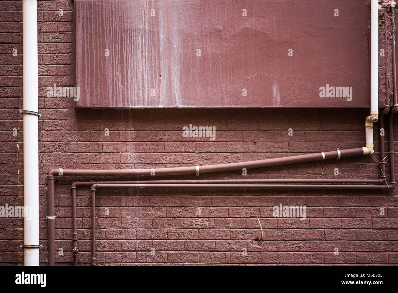 Grungy brown painted wall with pipes Stock Photo