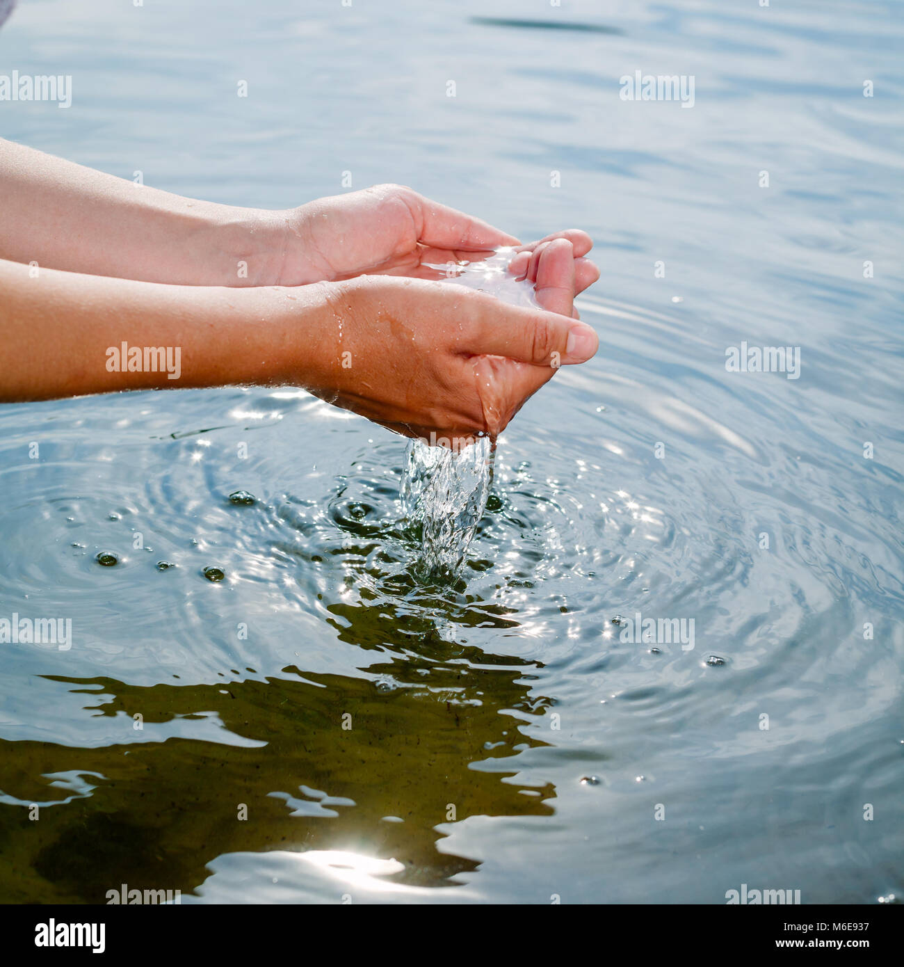 Woman taking raw unfiltered water from a natural source by cupped hands Stock Photo
