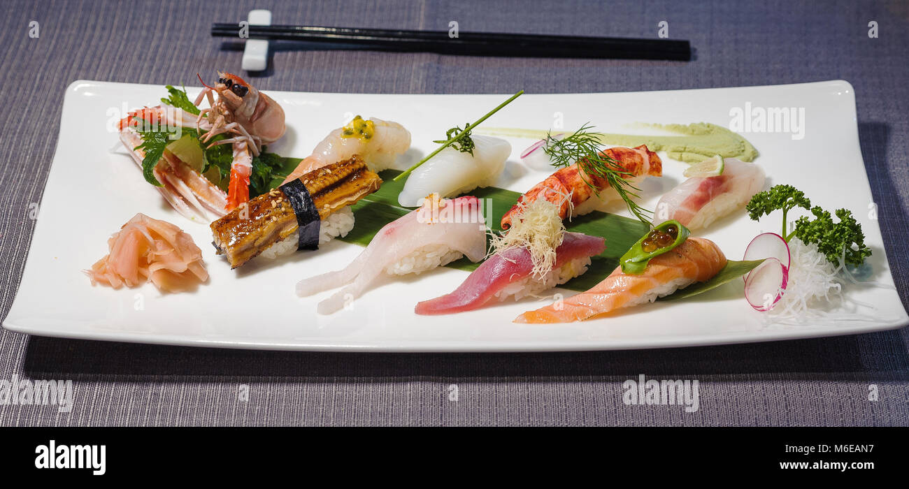 mix of different nigiri on a bamboo leaf served with daikon and radish