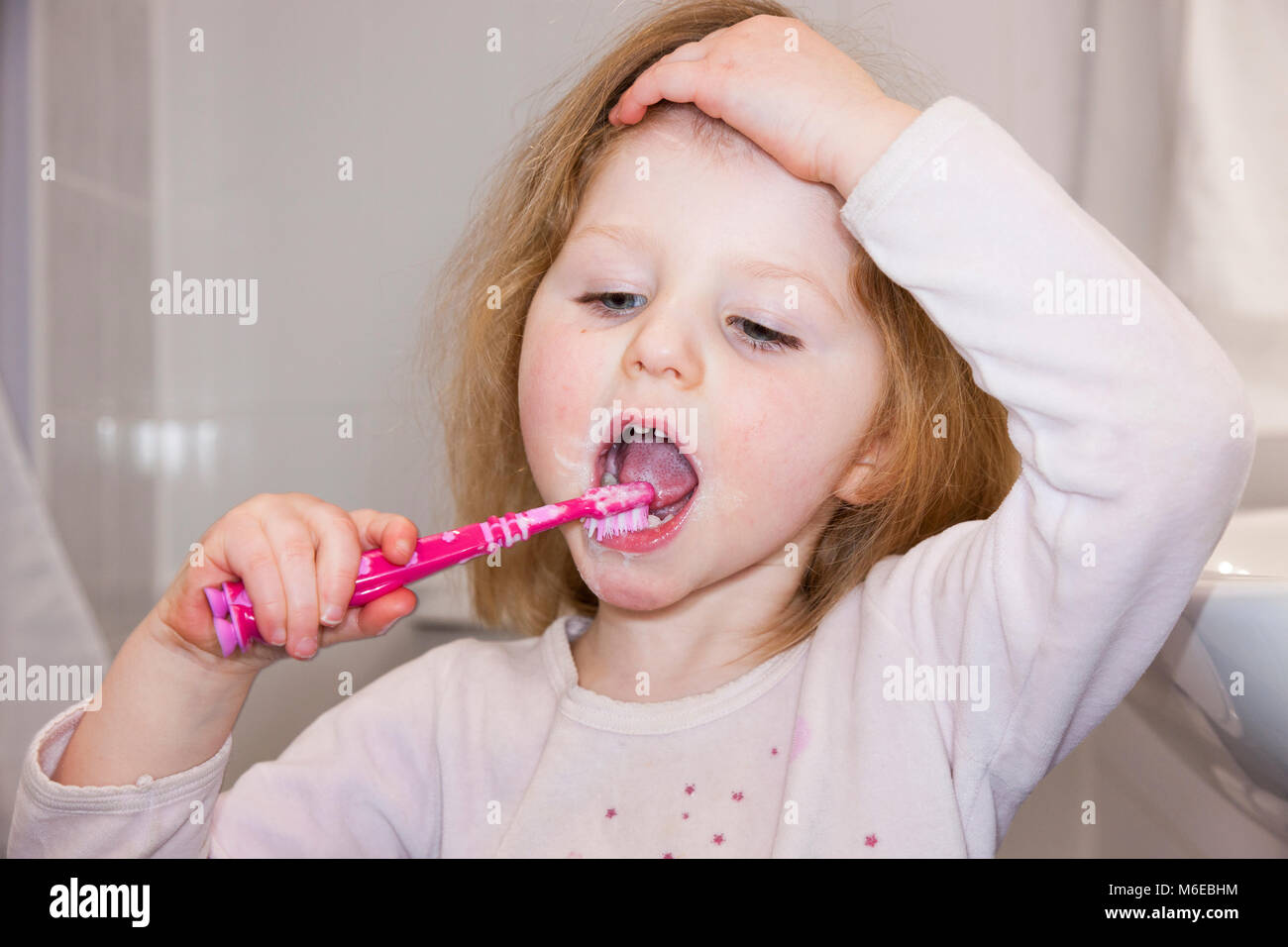 Three year old child / kid aged 3 years brushing her own milk teeth