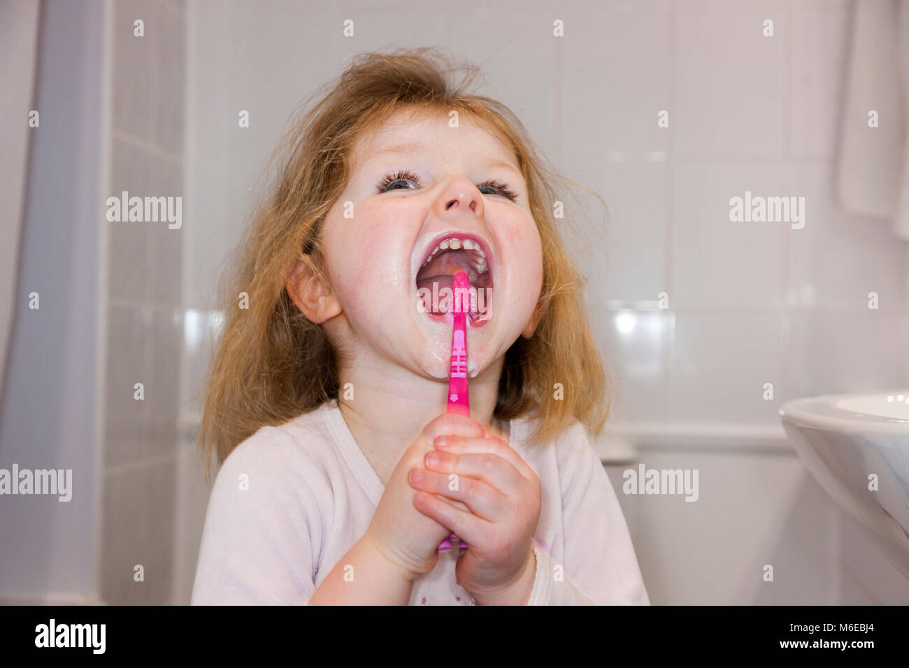 Three year old child / kid aged 3 years brushing her own milk teeth