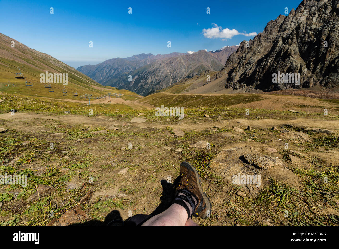 Tien Shen Mountains at Shymbulak Upper Piste Talgar pass near Almaty, Kazakhstanl Legs in foreground. Stock Photo