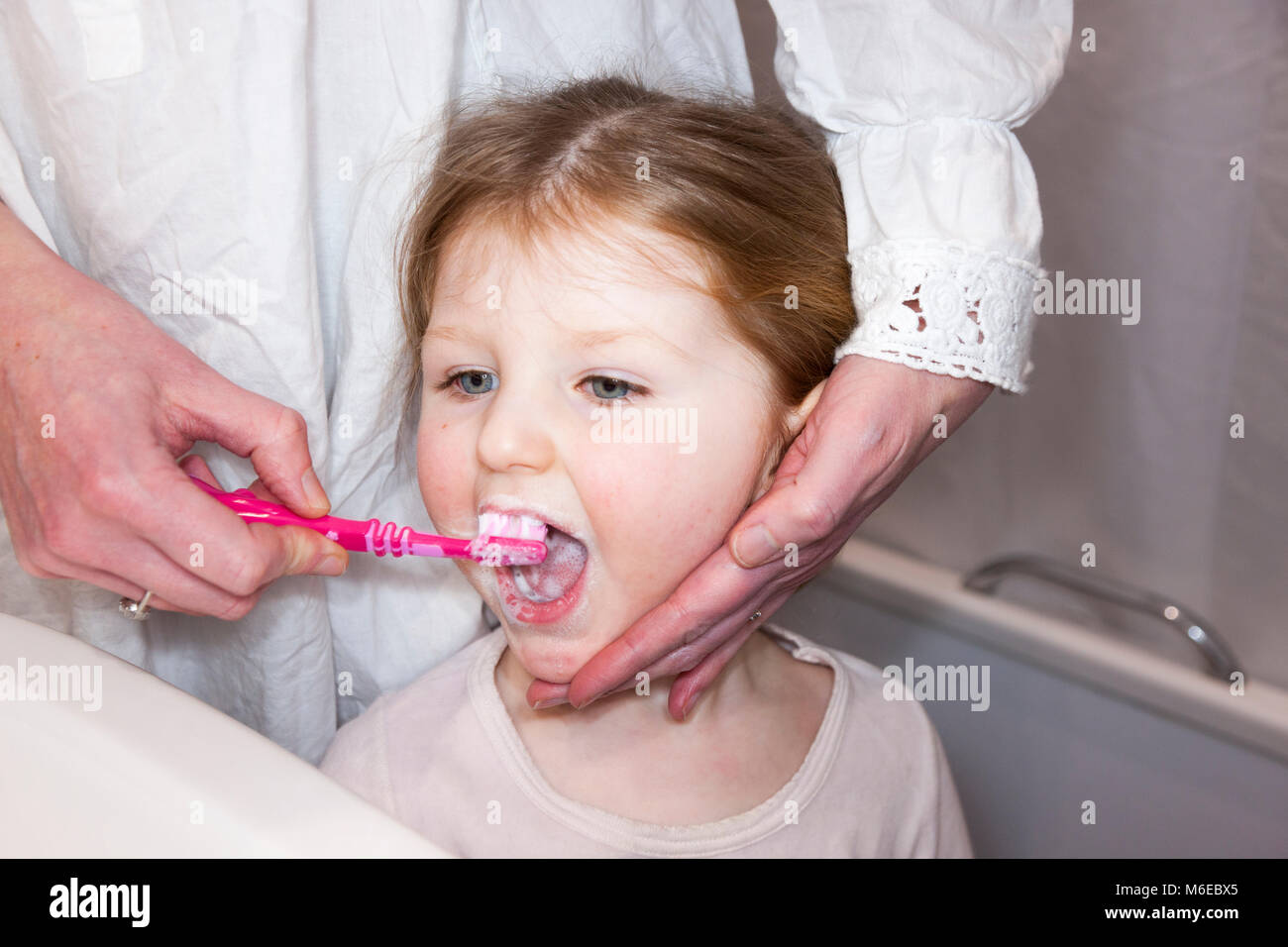 Three year old child / kid aged 3 years having her milk teeth brushed