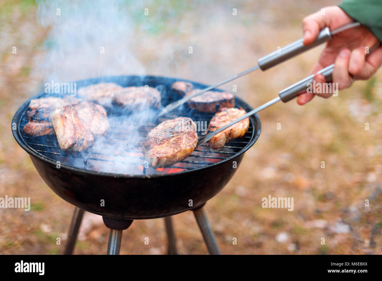 Man cooking, only hands, he is grilling meat or steak for a dish