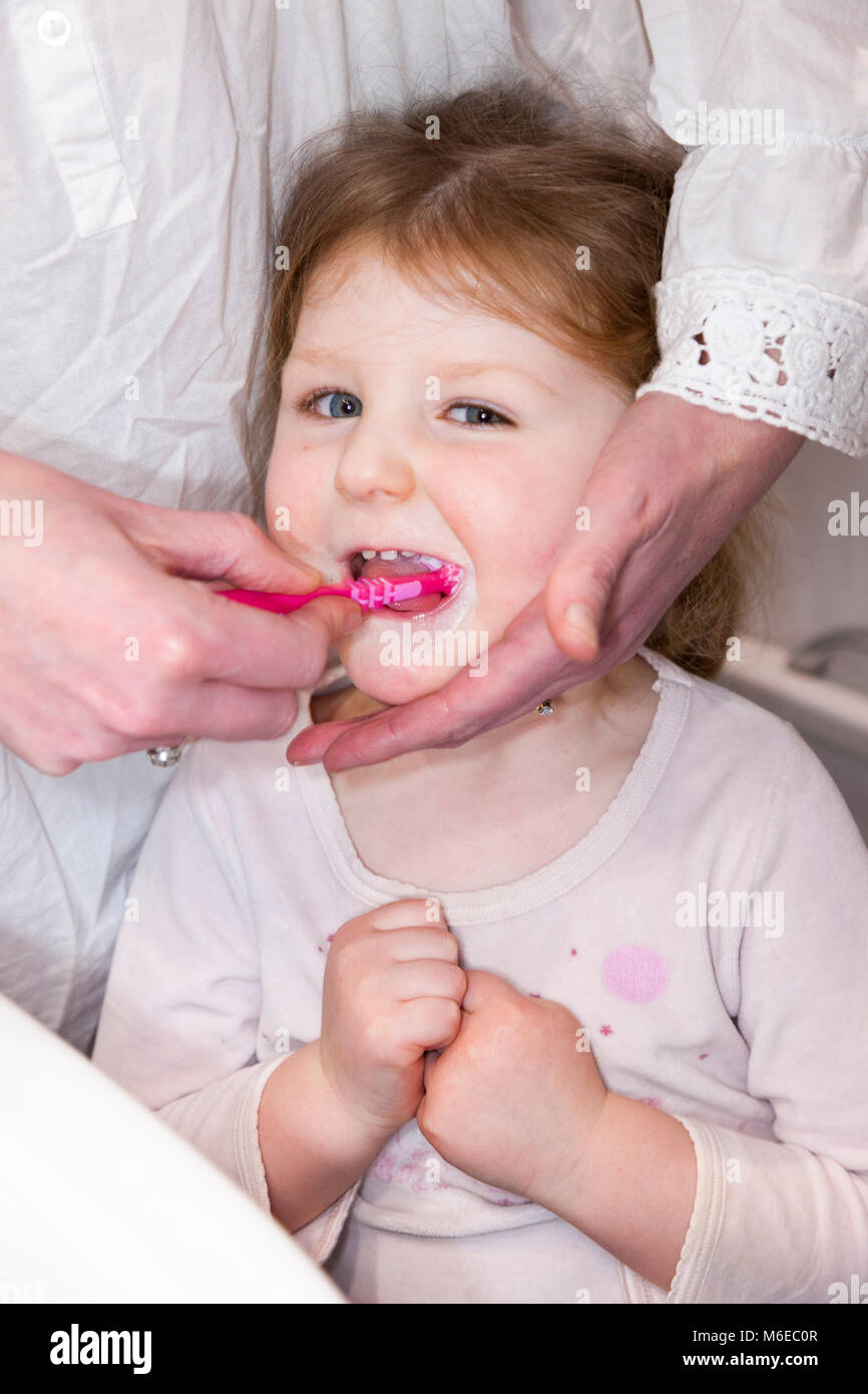 Three year old child / kid aged 3 years having her milk teeth brushed