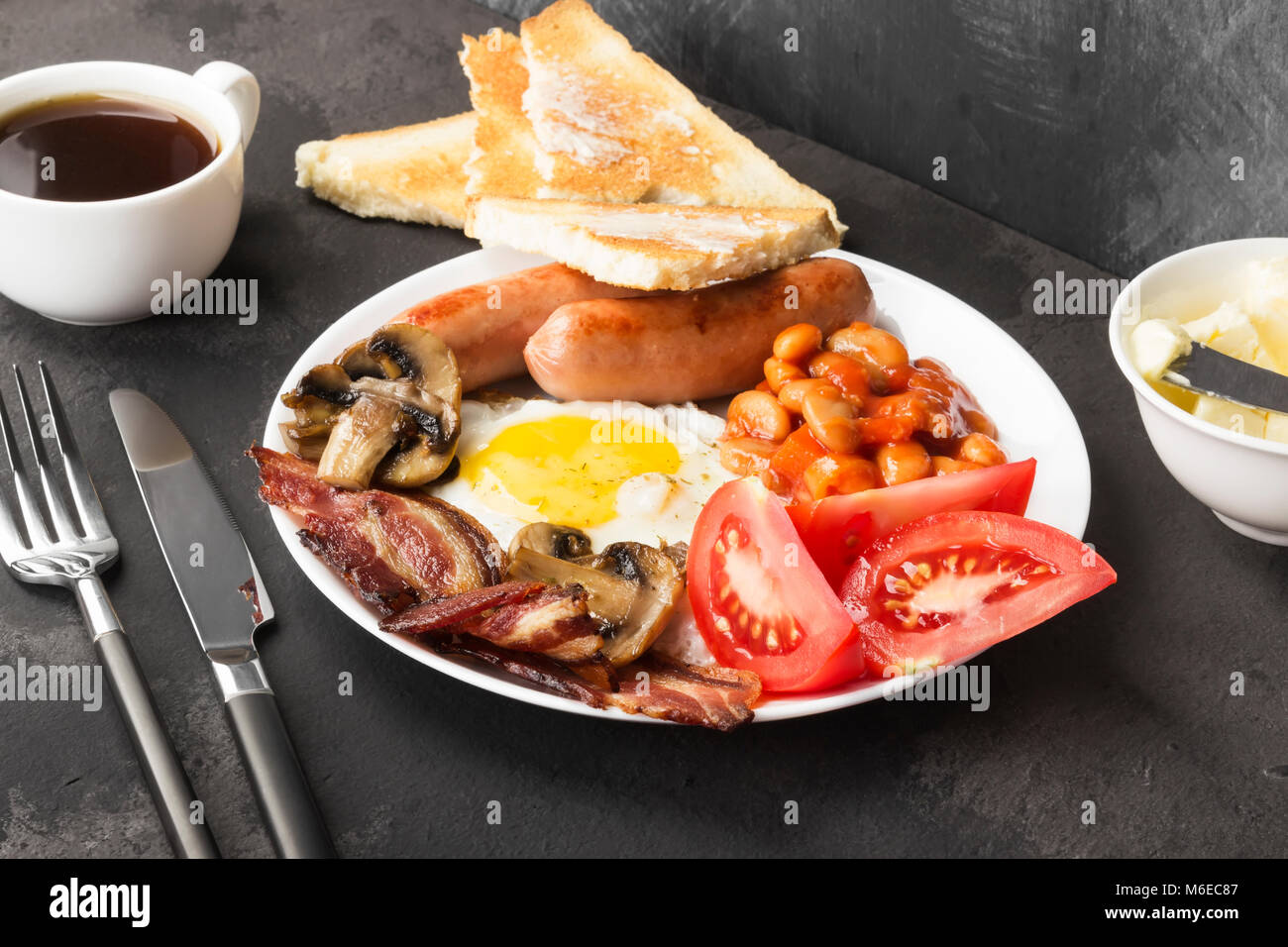 Traditional English breakfast bacon, sausages, fried eggs, tomatoes